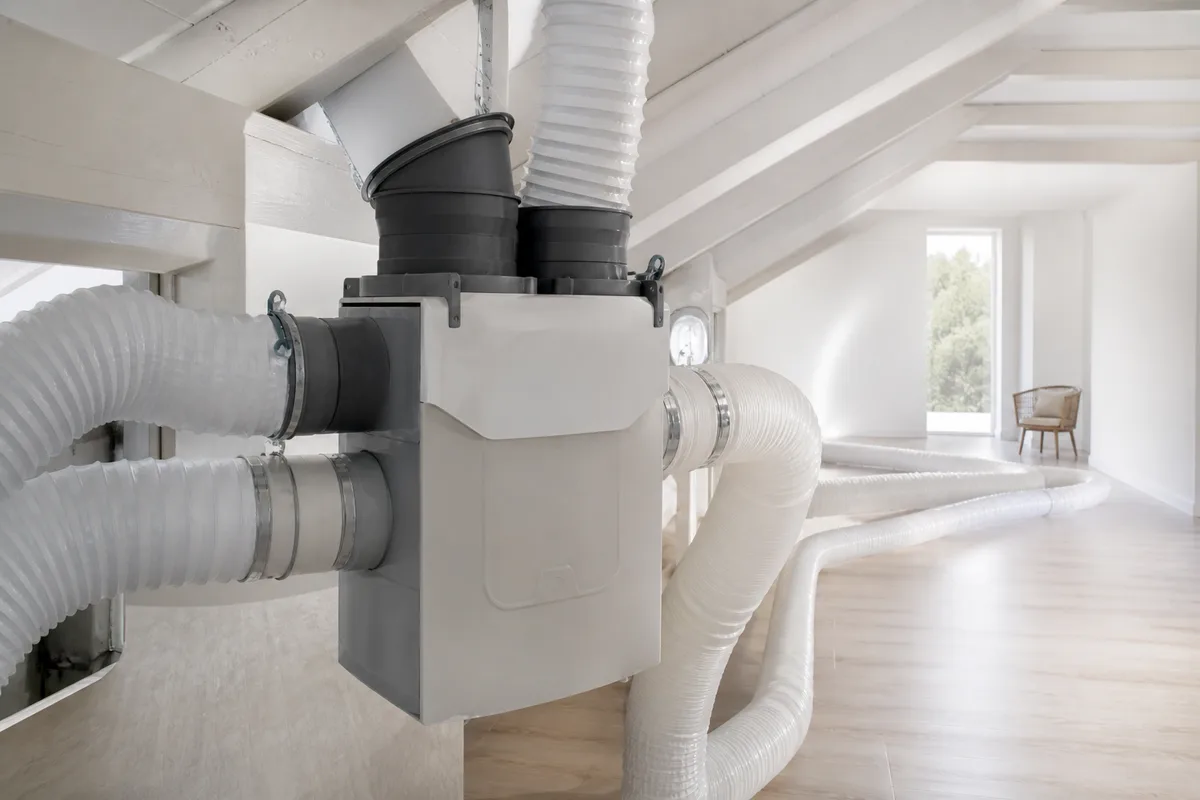 Groupe d’extraction de VMC simple flux installé dans des combles avec ses gaines souples